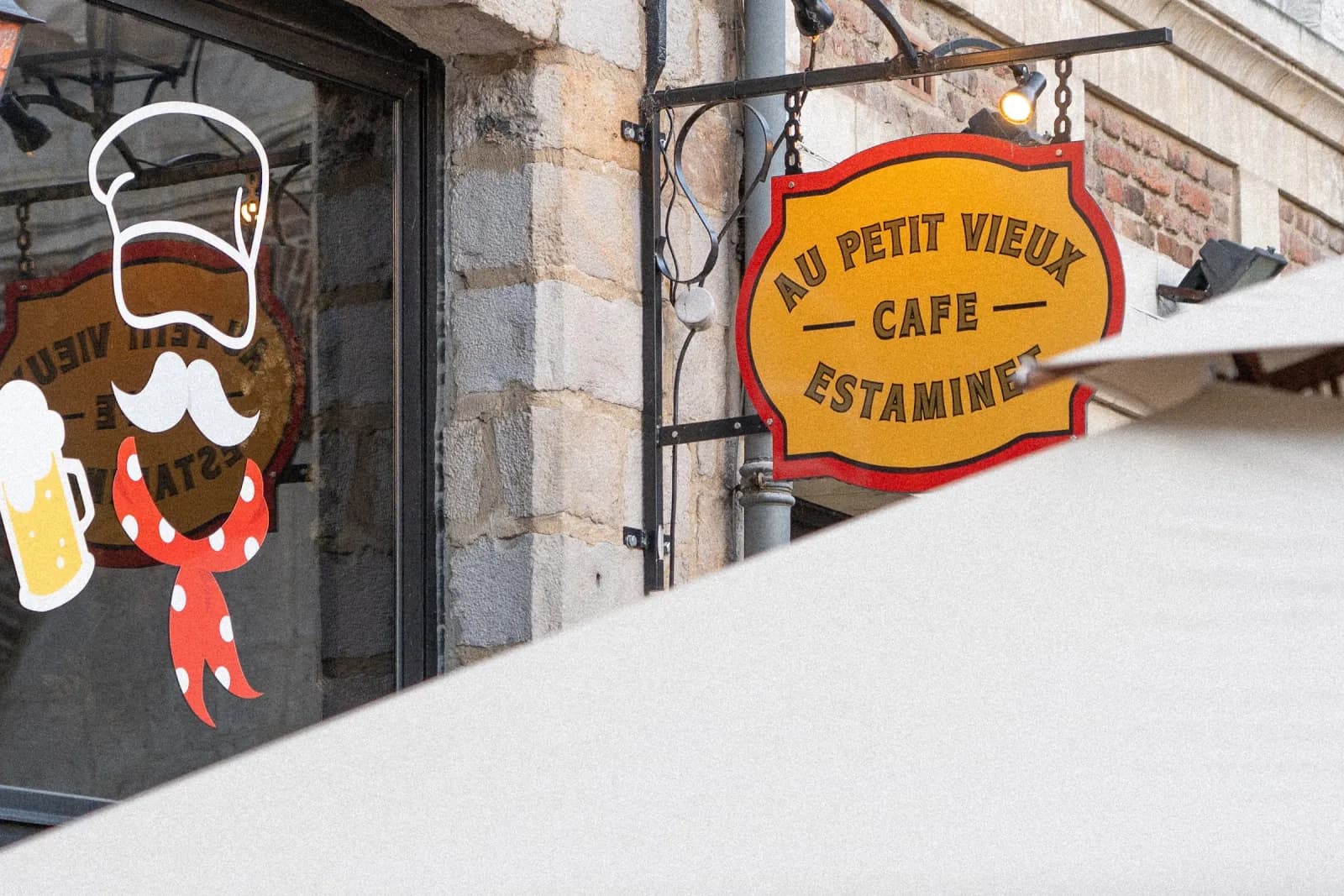 L'enseigne ovale du Petit Vieux et une lanterne de rue, place aux Oignons.